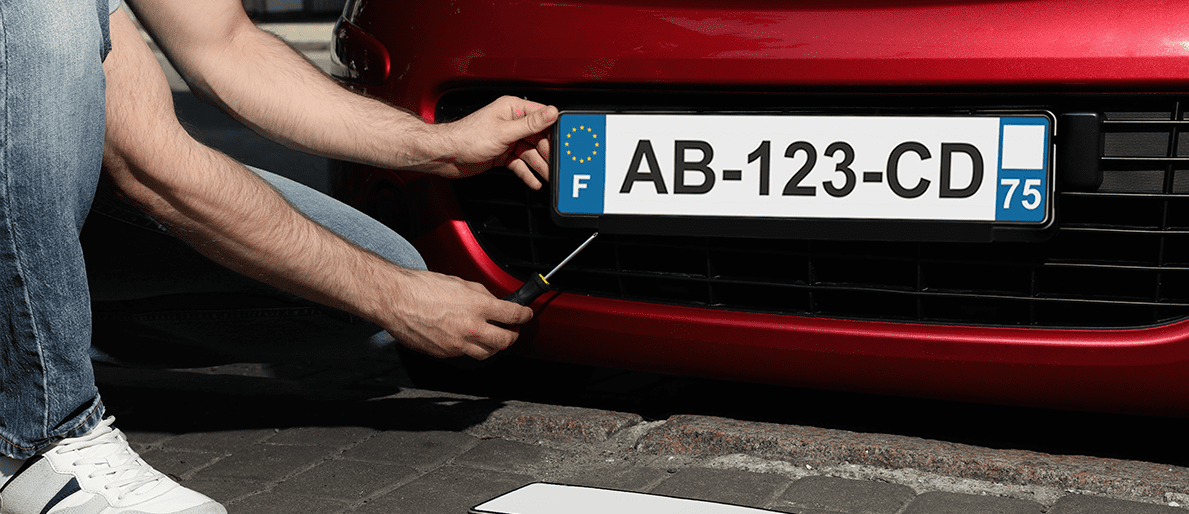 homme fixant une plaque d'immatriculation